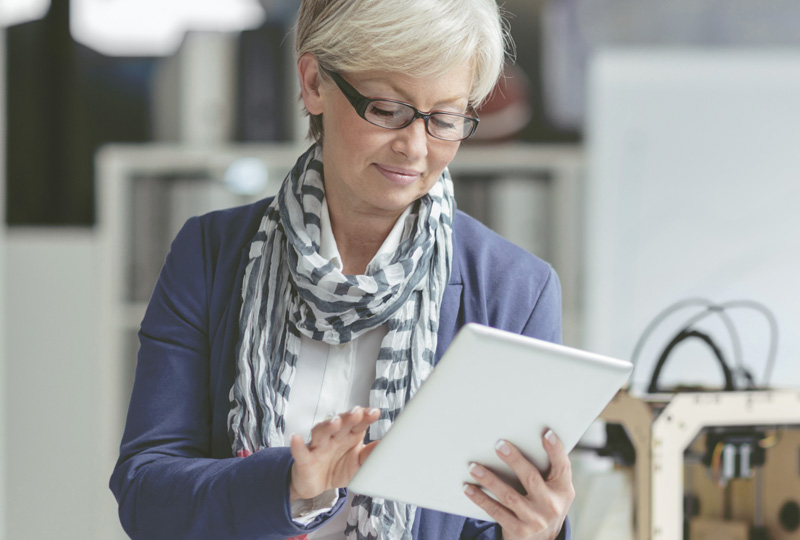 mature woman wearing glasses while using a tablet